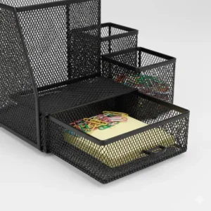A small sliding drawer at the base of a black desk organizer used for storing paperclips and sticky notes.